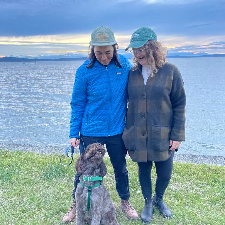 Kelly Kraus Lee, Director of Development, Education and Policy posses with her wife and dog near a lake on a camping roadtrip.  