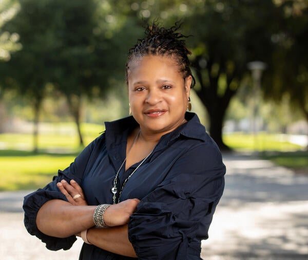 Vice Chancellor for University Advancement, Monique Dozier, poses with crossed-arms and smiles on a sunny day at UC Riverside