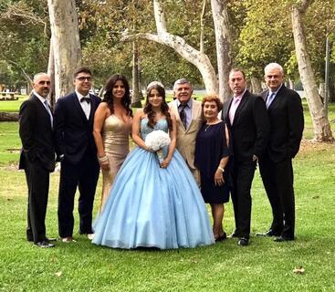 UCR's Assistant Vice Chancellor for Alumni and Constituent Relations, Jorge Ancona, far right, poses with his family during a family member's quinceañera. The celebrant is wearing a blue dress and holding a bouquet of white flowers.